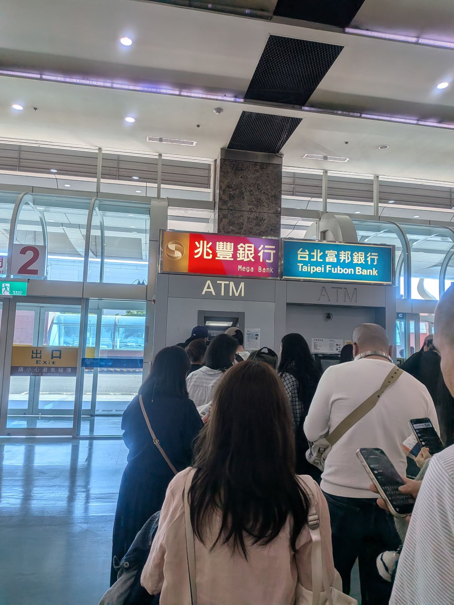 高雄国際空港の到着ホールの ATM に並ぶ行列